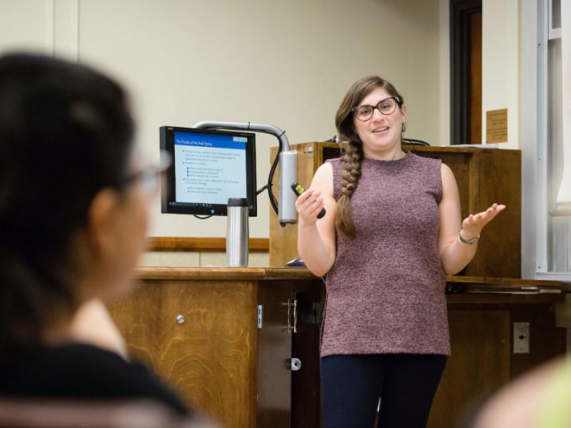 Female professor lectures to political science class in Gregory Hall.